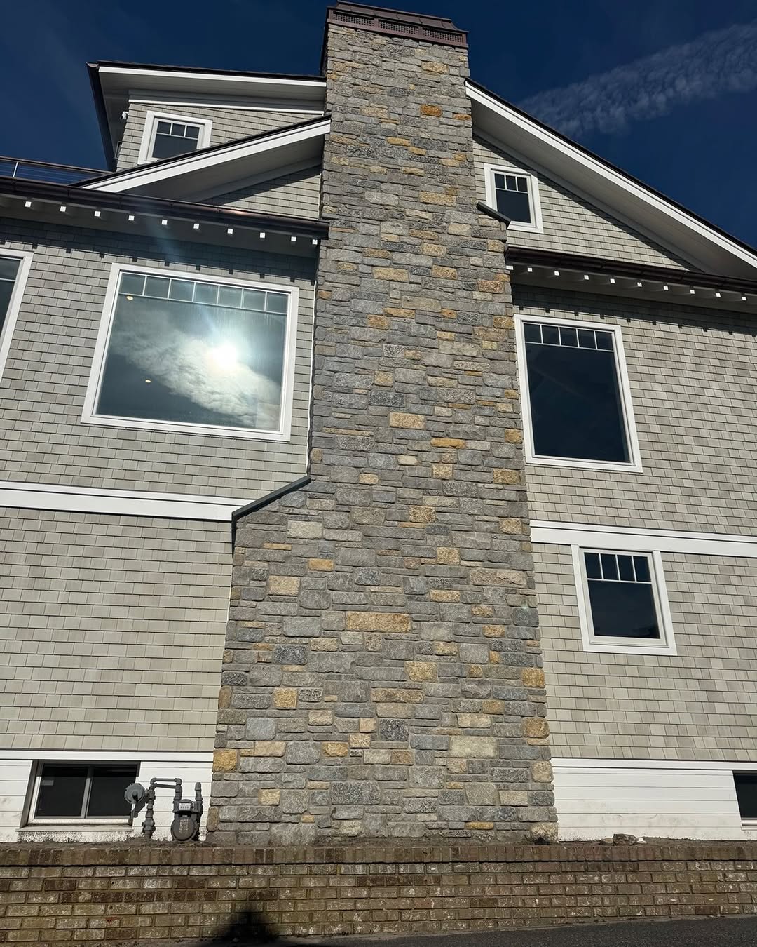 Stone veneer chimney on a shingle house